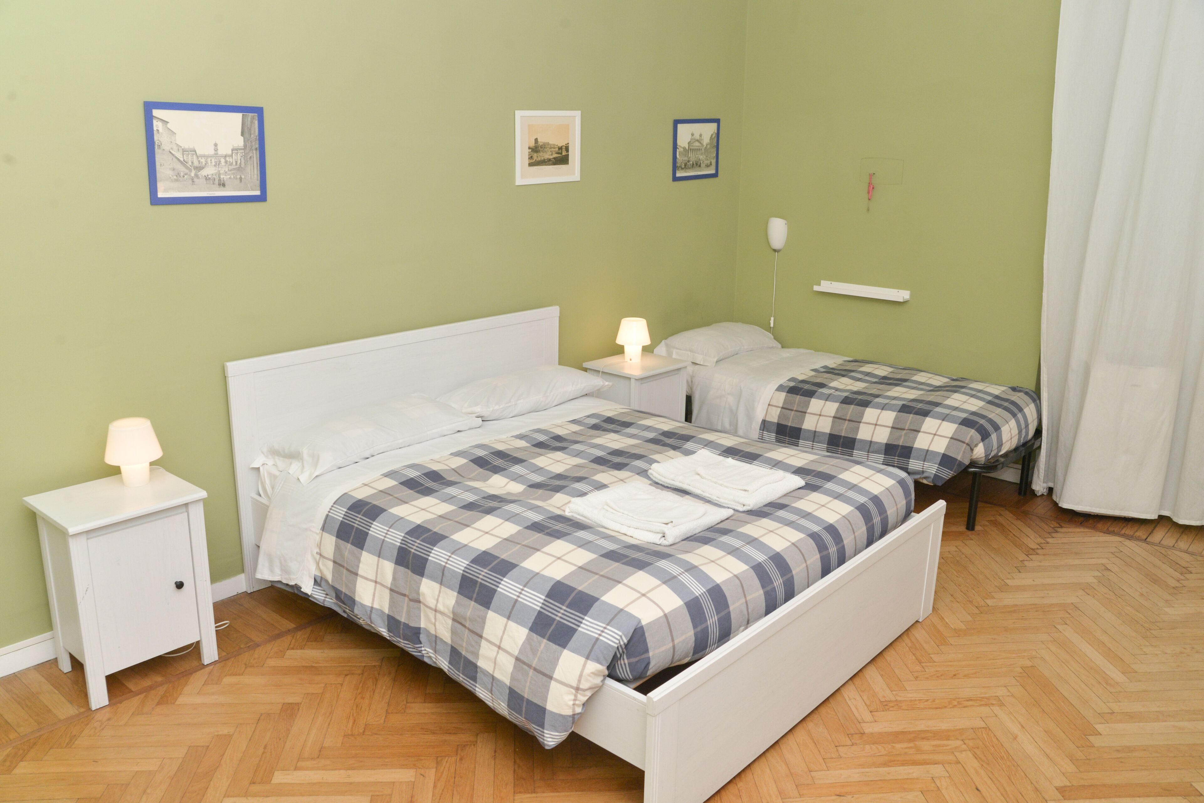 Une chambre avec deux lits, une table de chevet et une petite table de nuit avec une lampe.