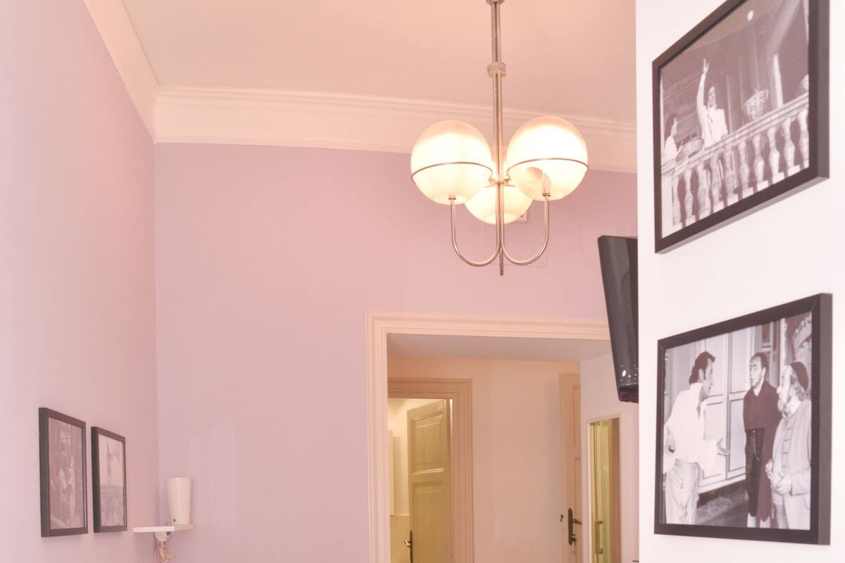 A bedroom with a bed, bedside table, and a hanging light fixture.