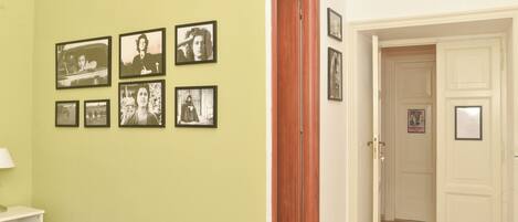 Una habitación con una cama, una mesita de noche y una pared con fotografías enmarcadas.