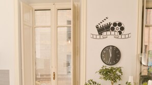 A compact kitchen with a round table, four chairs, a potted plant, and a wall clock. - Colazione Al Vaticano (Rome)
