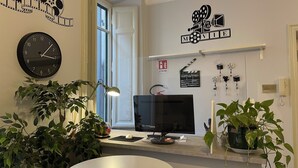 A room with a round table, a desk with a computer, a clock, and a film reel decoration. - Colazione Al Vaticano (Rome)