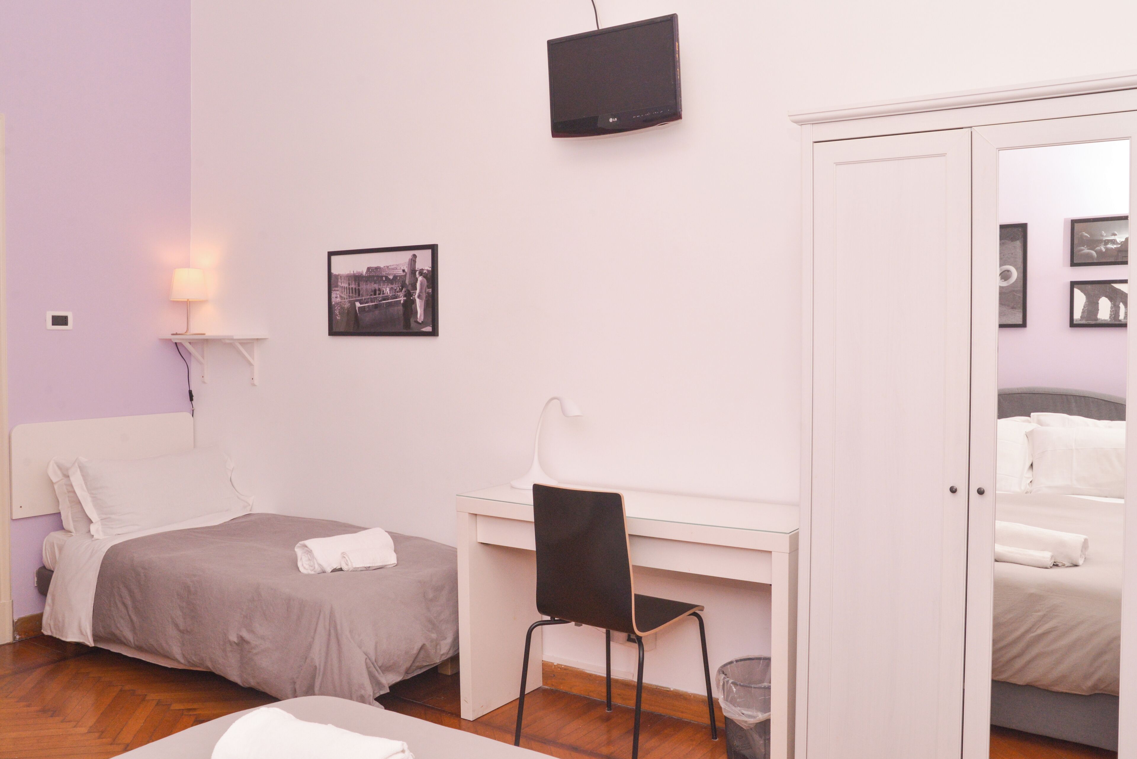 Une chambre à coucher avec un lit, un bureau, une chaise, une télévision et un tableau au mur.