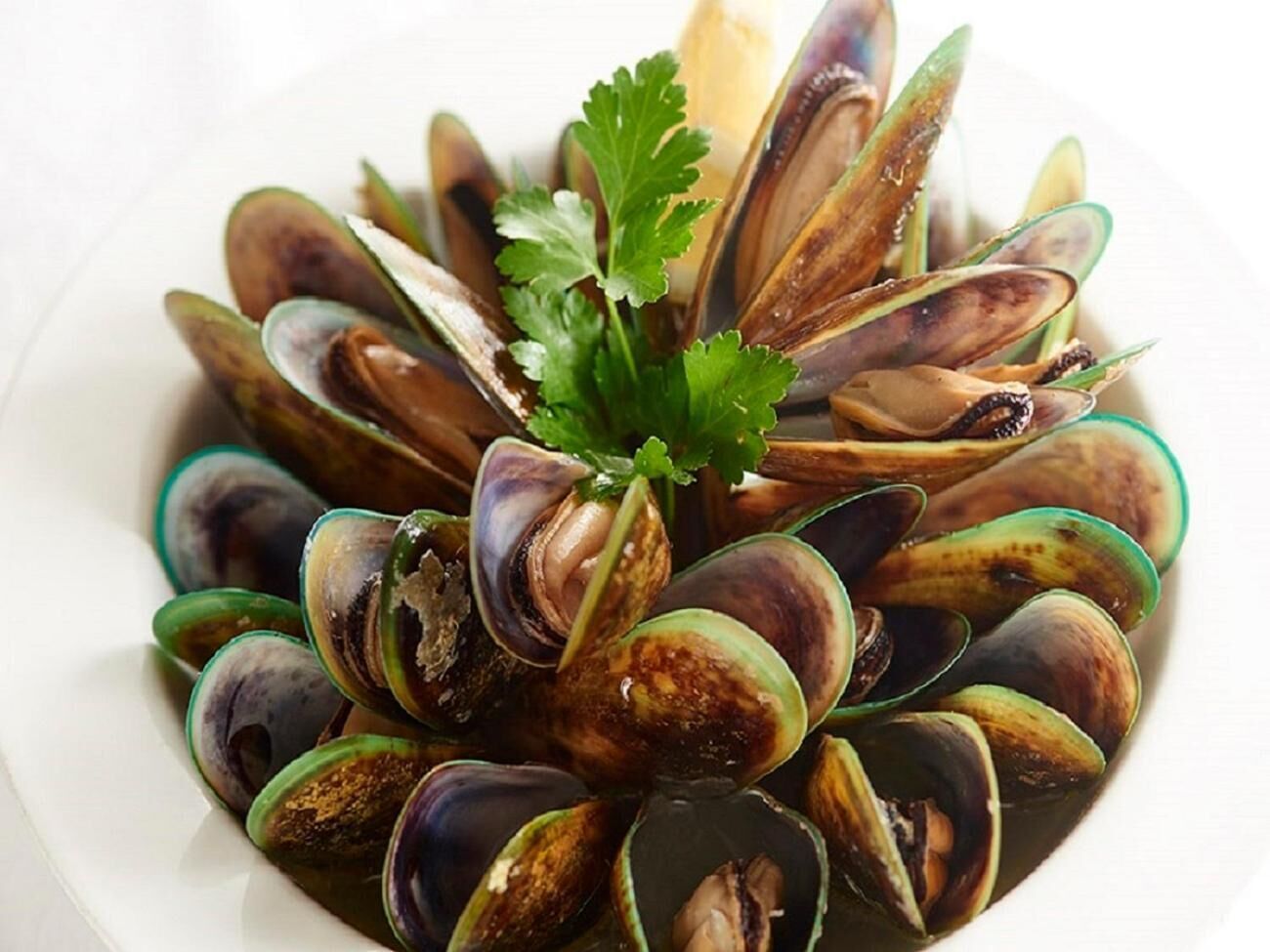 A plate of cooked mussels garnished with parsley.
