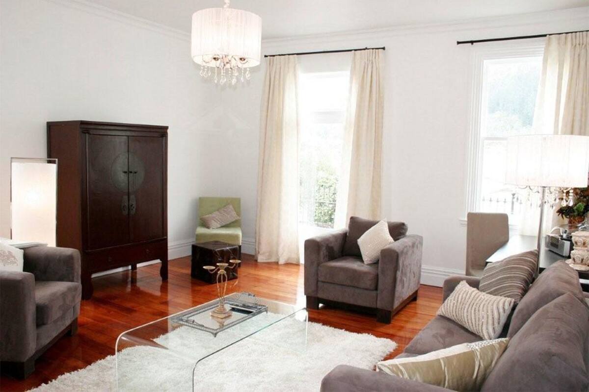 A living room with a large wooden cabinet, a glass coffee table, and two grey sofas.