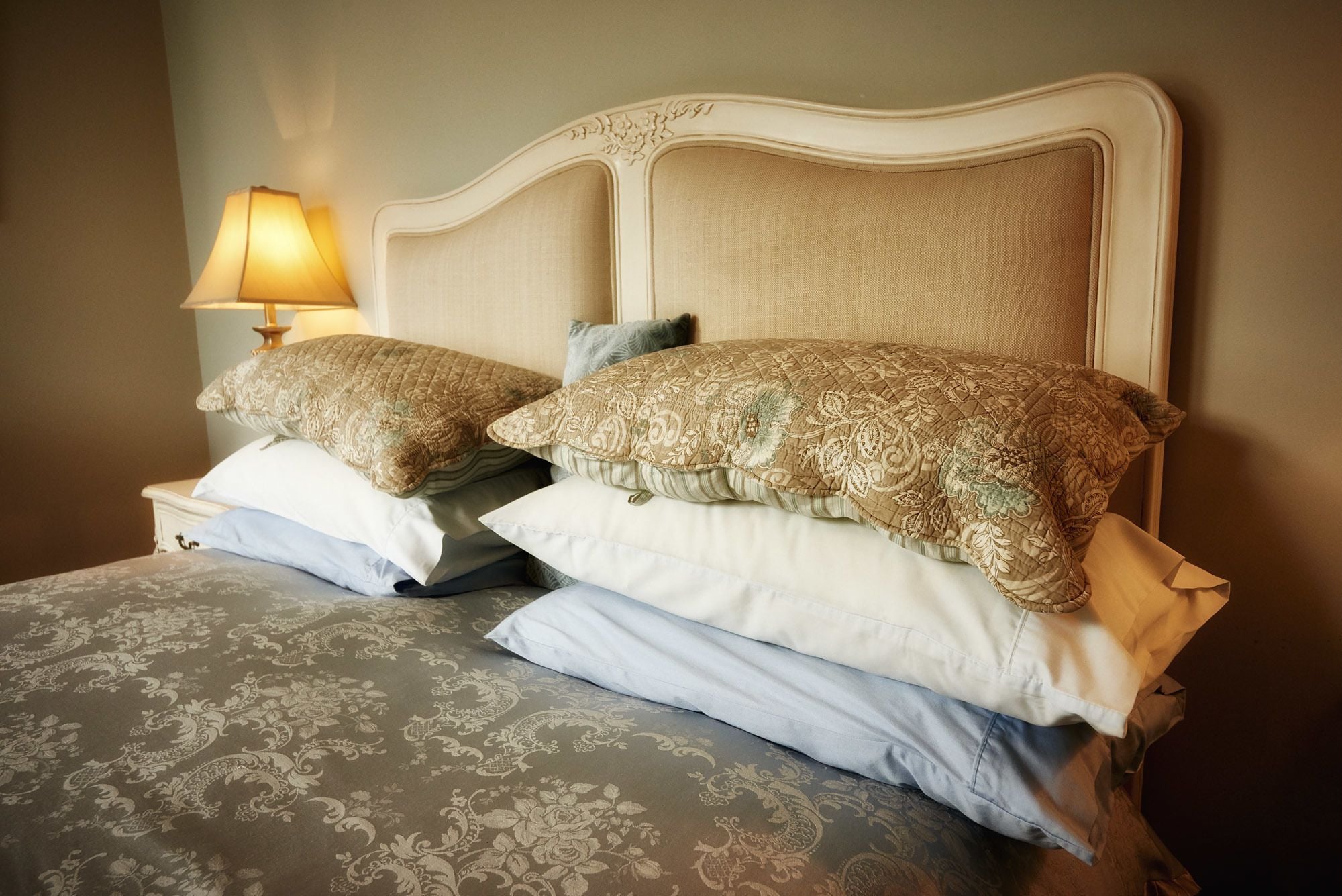 A bed with a patterned bedspread and two decorative pillows.