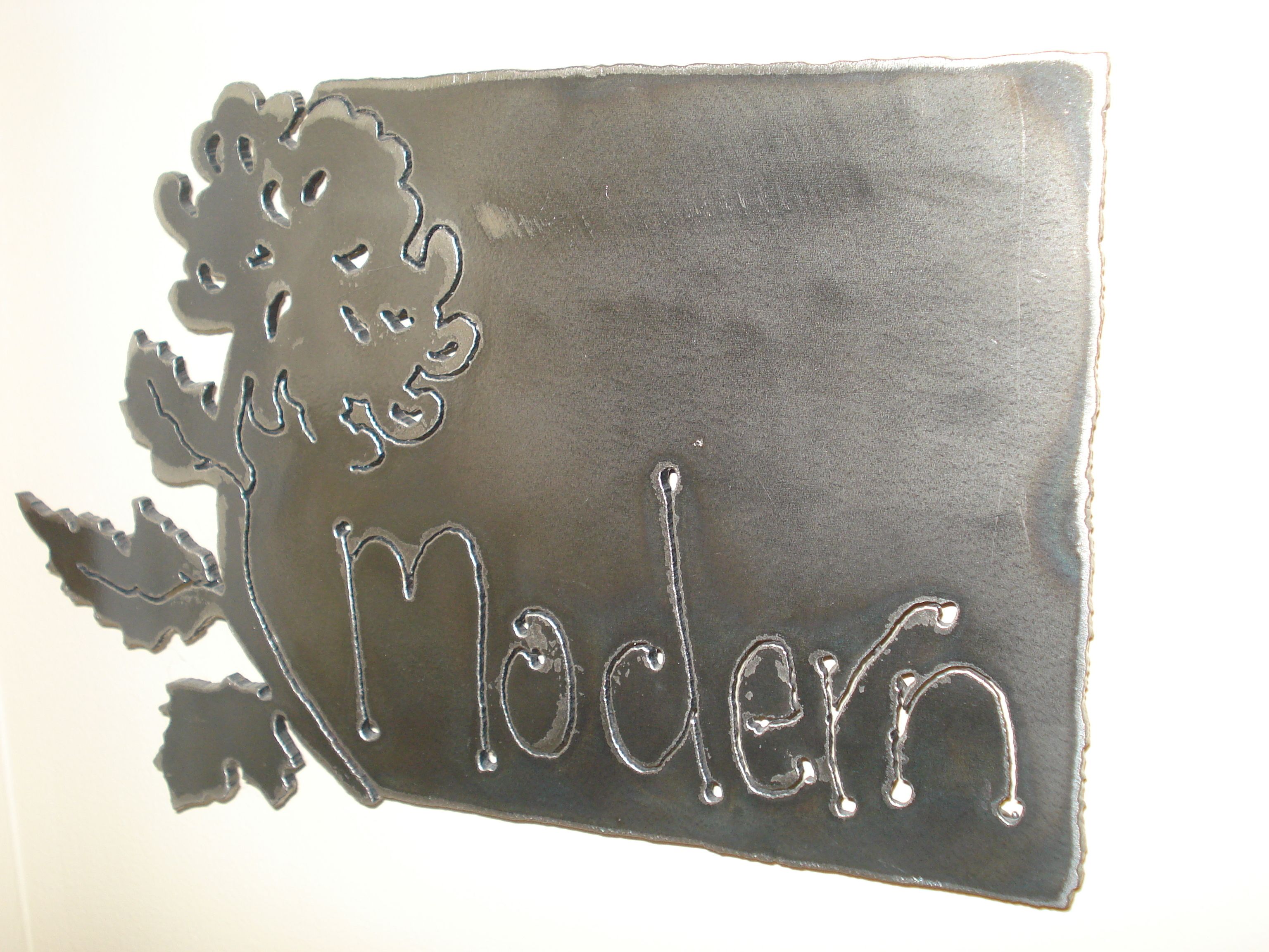 A metal sign with the word "Modern" and a tree design.