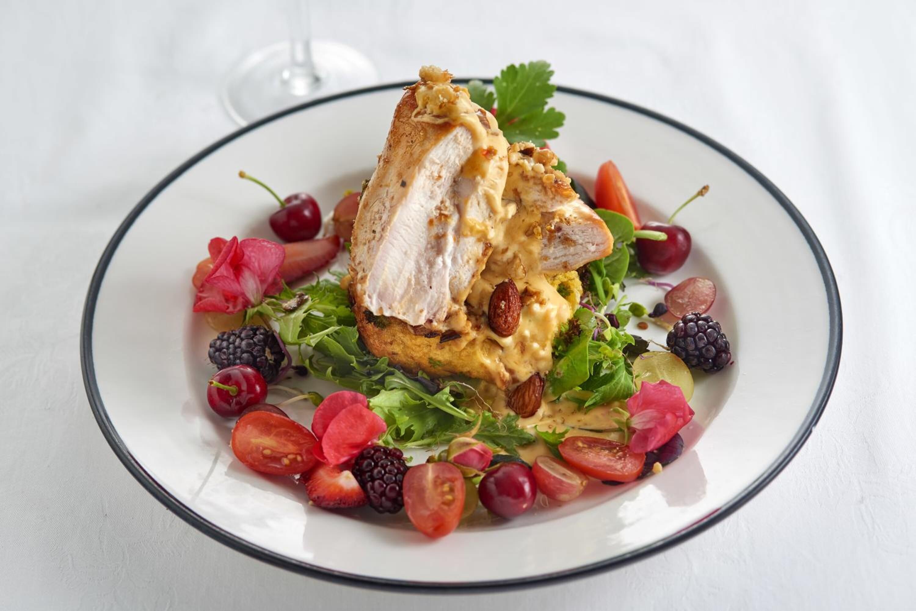 A plate of food with a piece of meat, greens, and berries.