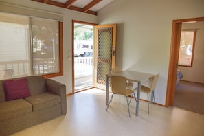 A room with a sofa, a table, and chairs. There is a sliding glass door leading outside. - BIG4 Crystal Brook Tourist Park (Doncaster East)