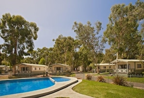 A pool area with a curved edge, surrounded by a fence, and adjacent to mobile homes with a covered patio. - BIG4 Crystal Brook Tourist Park (Doncaster East)