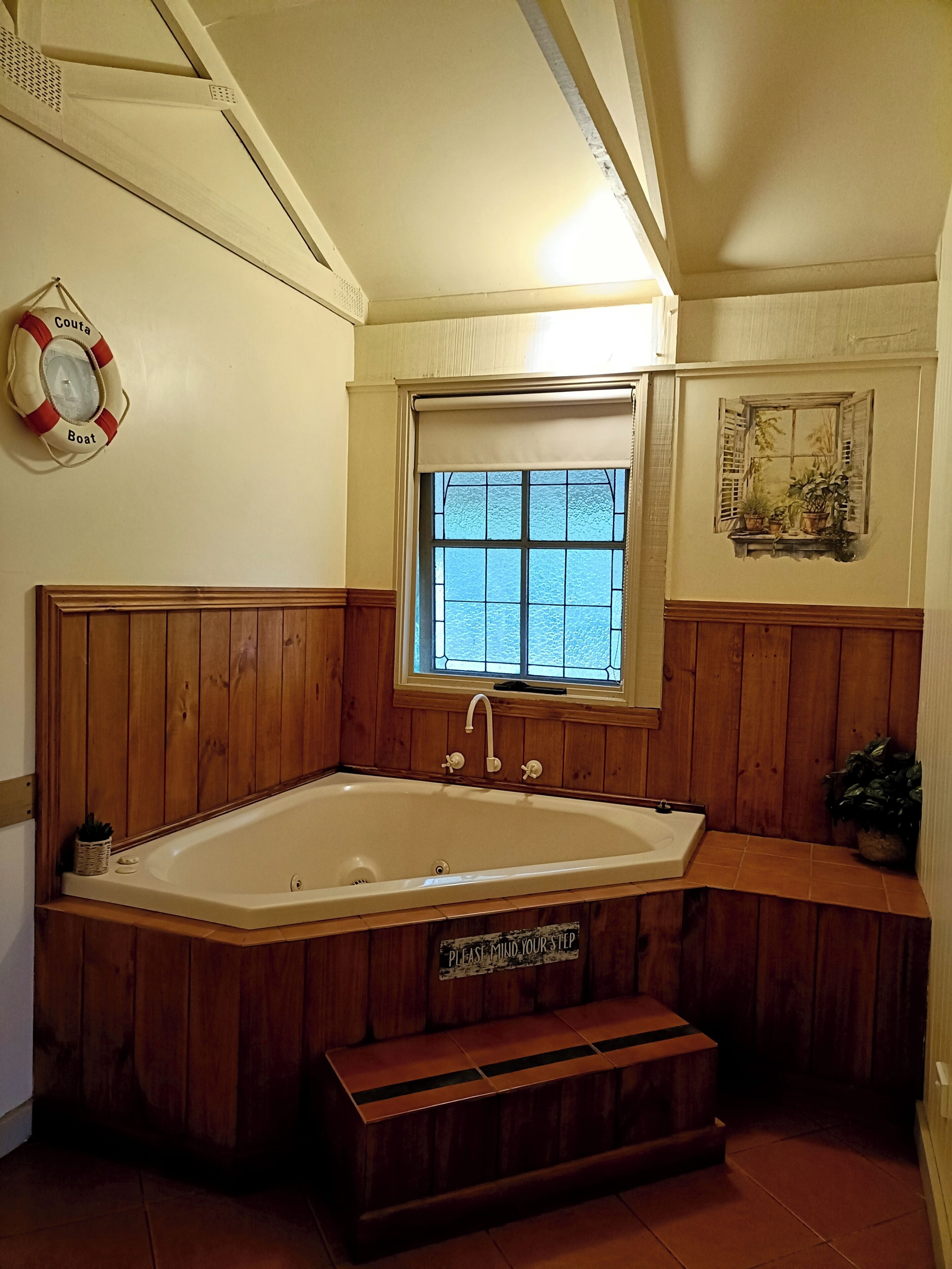 Un baño con una bañera independiente, un ventanal con vistas, un flotador en la pared y un banco de madera.