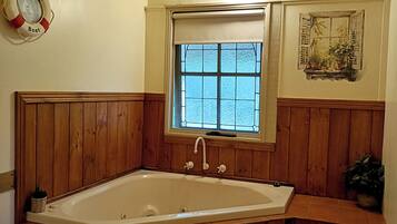 Un baño con una bañera independiente, un ventanal con vistas, un flotador en la pared y un banco de madera.