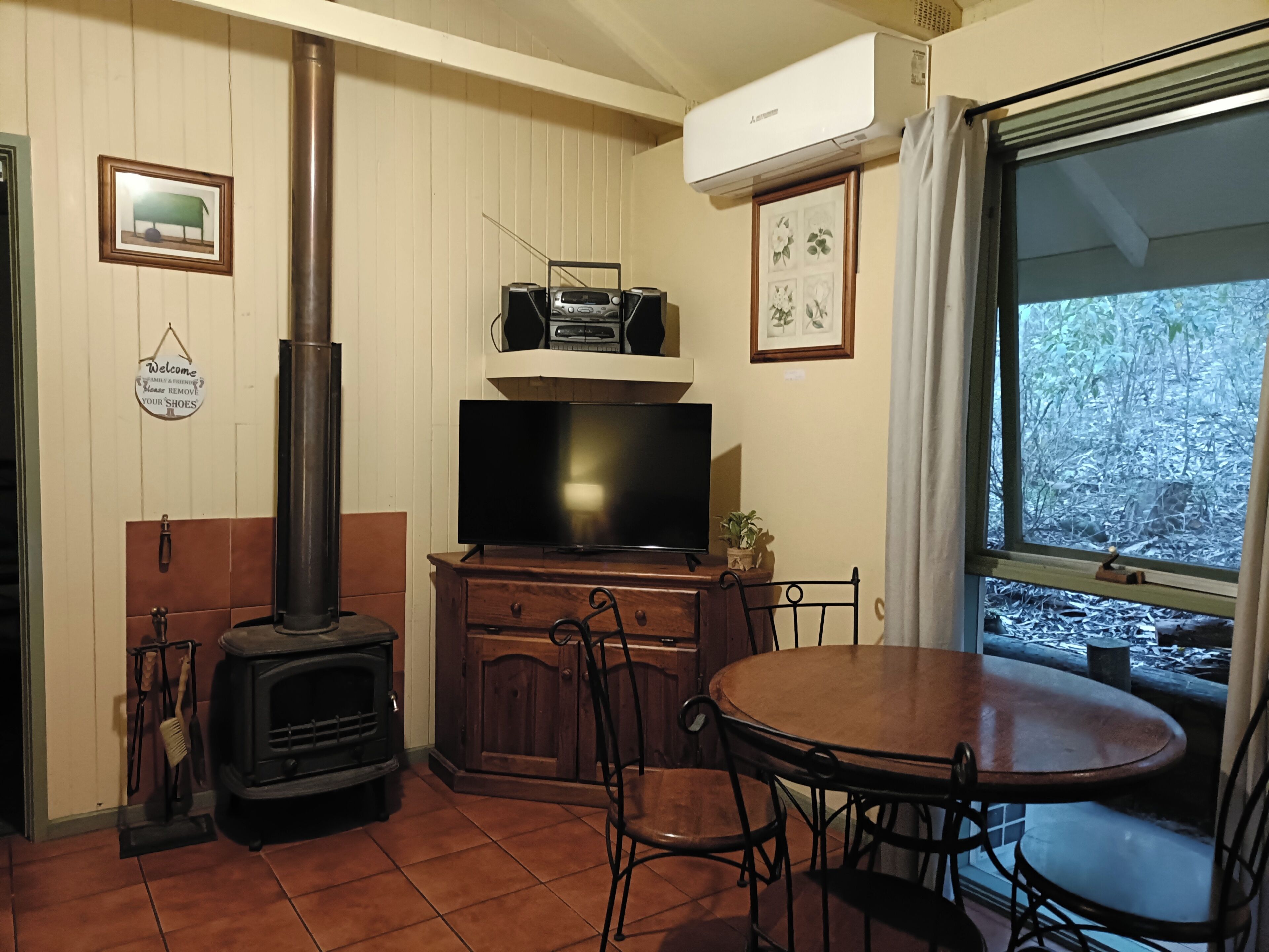 A cozy living room with a wood-burning stove, a television, and a dining table.
