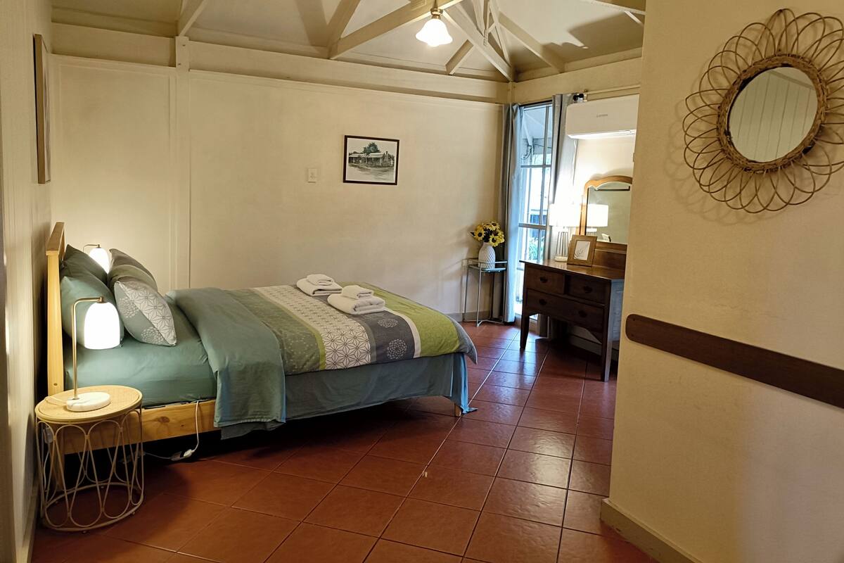 A bedroom with a bed, bedside table, and a dresser.