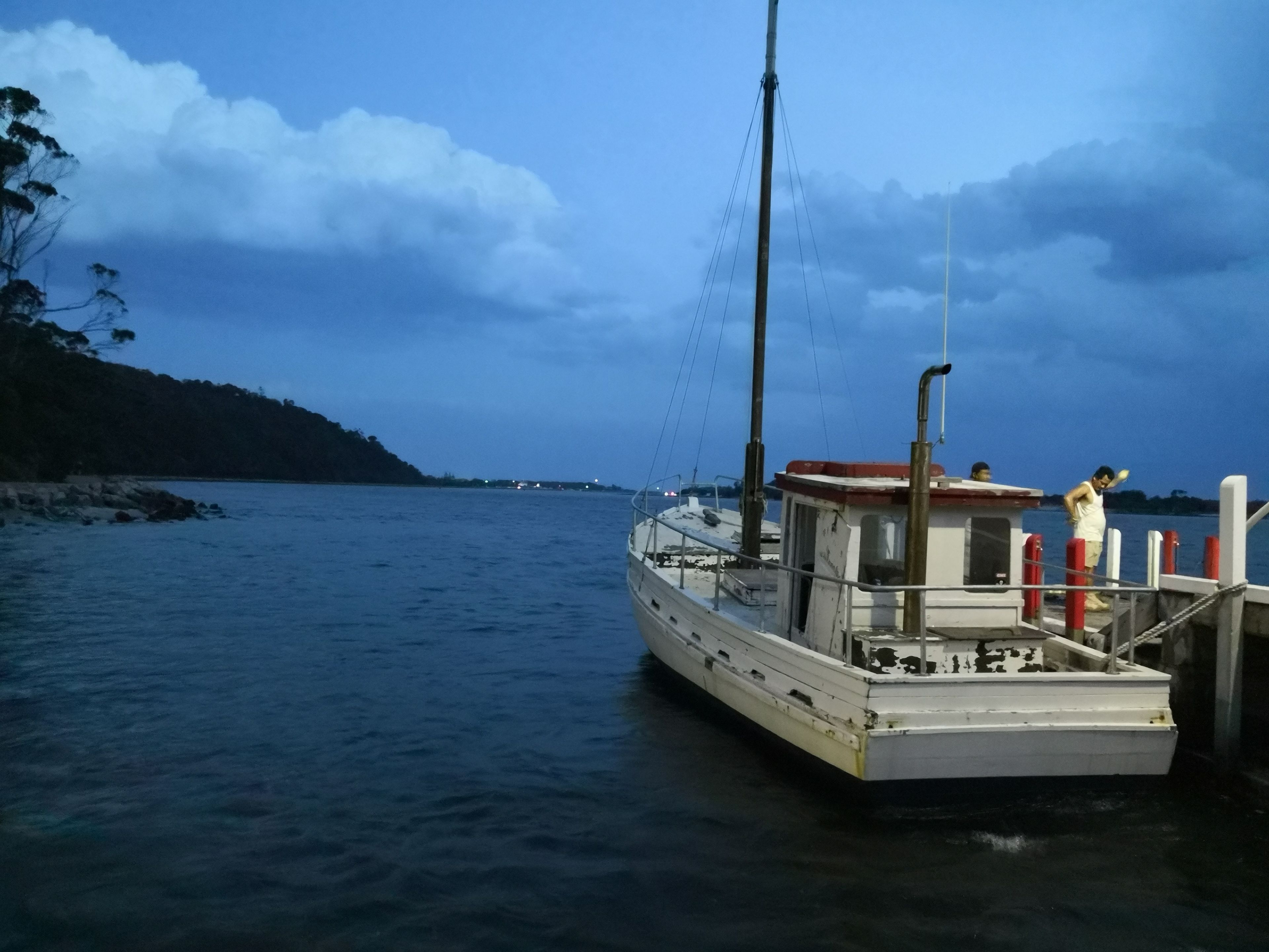 Un bateau était amarré à un quai, et une personne se tenait sur le pont.