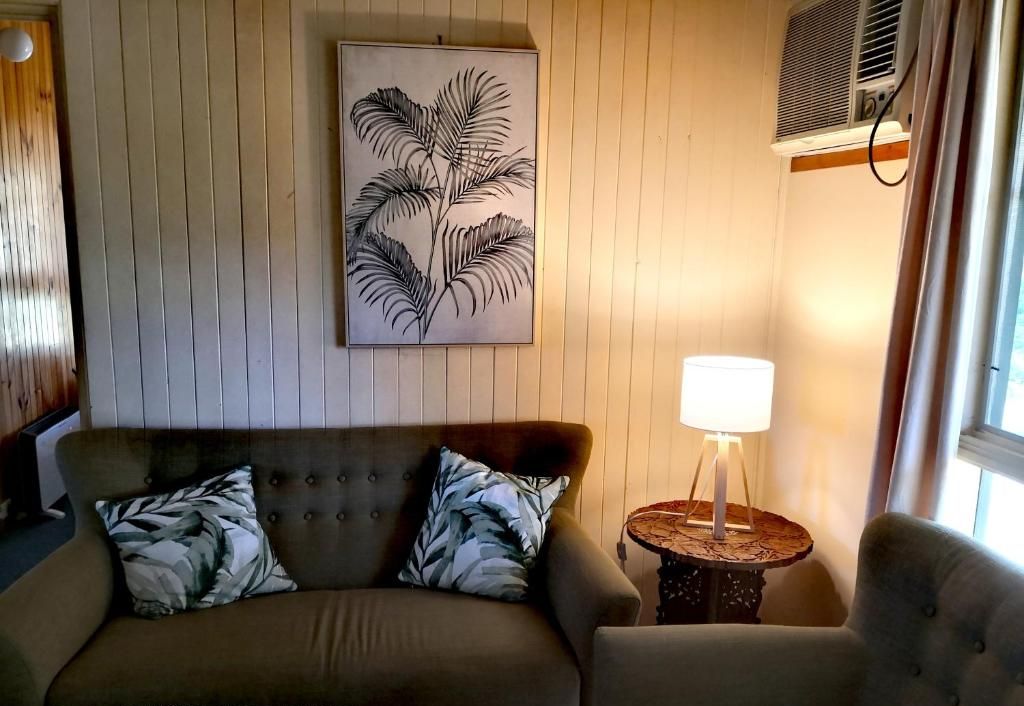 A cozy living room with a sofa, armchair, and a wall-mounted artwork.