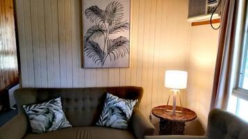 A cozy living room with a sofa, armchair, and a wall-mounted artwork.