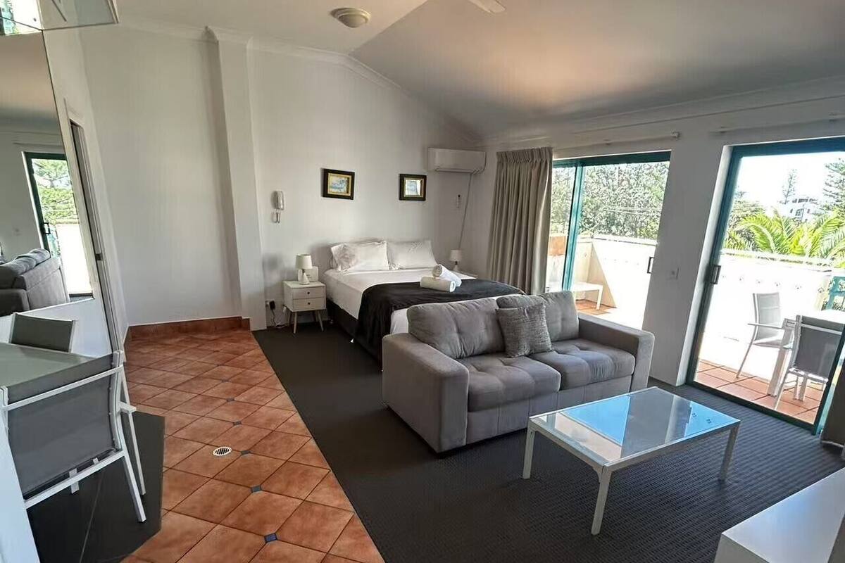 Una habitación de hotel moderna con una cama, un sofá, una mesa de centro y un comedor.