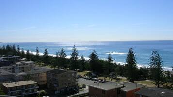 A coastal residential area with buildings, a road, and a view of the ocean.