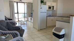 Un espacio habitable compacto con kitchenette, una zona de comedor con mesa y sillas, y un sofá.
