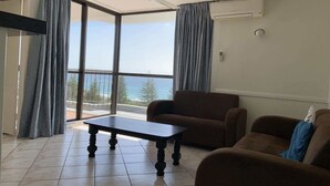 Amplia sala de estar con un gran ventanal corredizo que da a un balcón con vistas al mar.