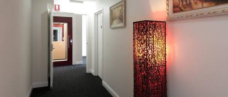 A hallway with a red door, a framed painting, and a decorative light fixture.