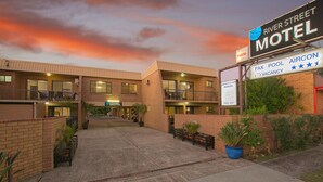 Un motel con un cartel que indica servicios como fax, piscina, aire acondicionado, estacionamiento techado y wifi gratuito.