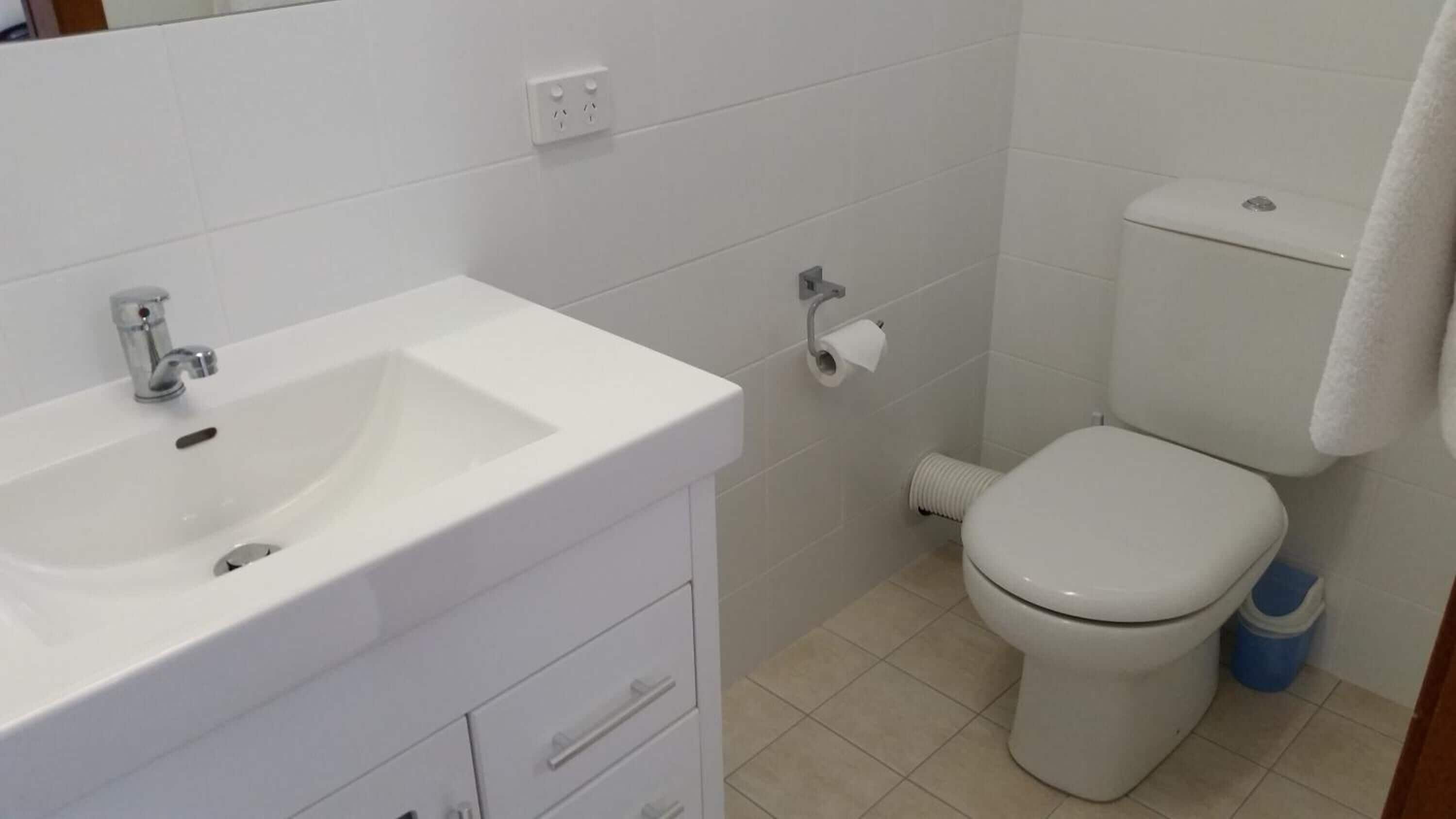 A bathroom with a white sink, toilet, and a towel hanging on the wall.