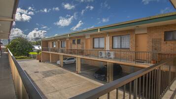 Un motel con estacionamiento techado, varias habitaciones y un balcón.