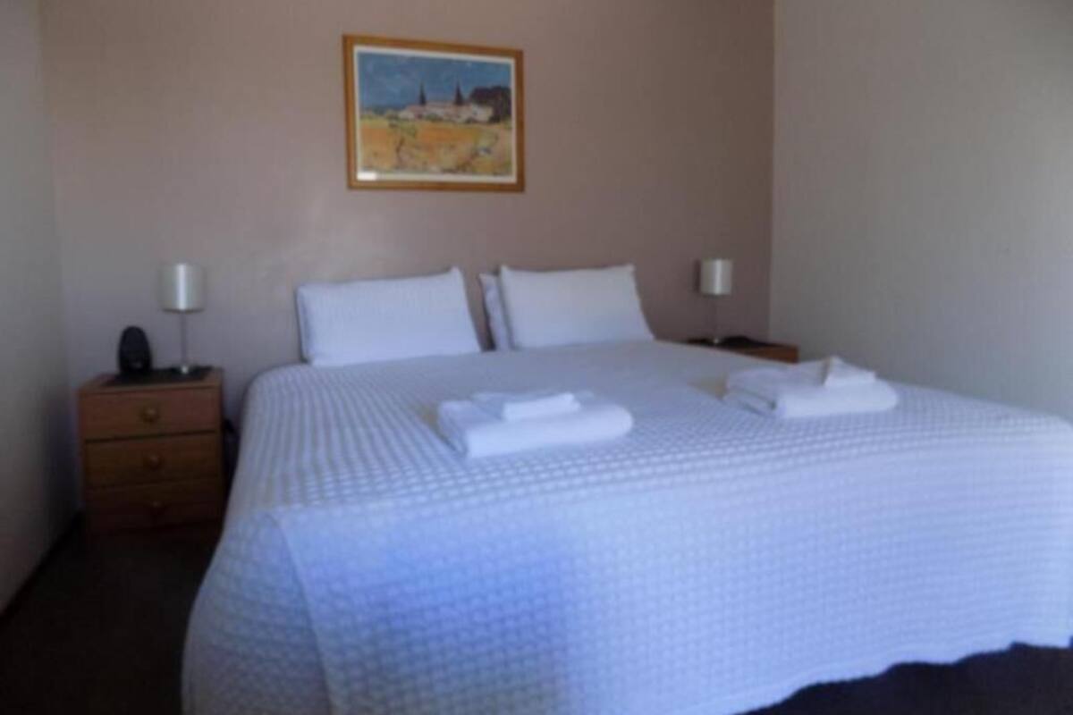 Une chambre d’hôtel avec un grand lit, deux tables de chevet et un tableau au mur.
