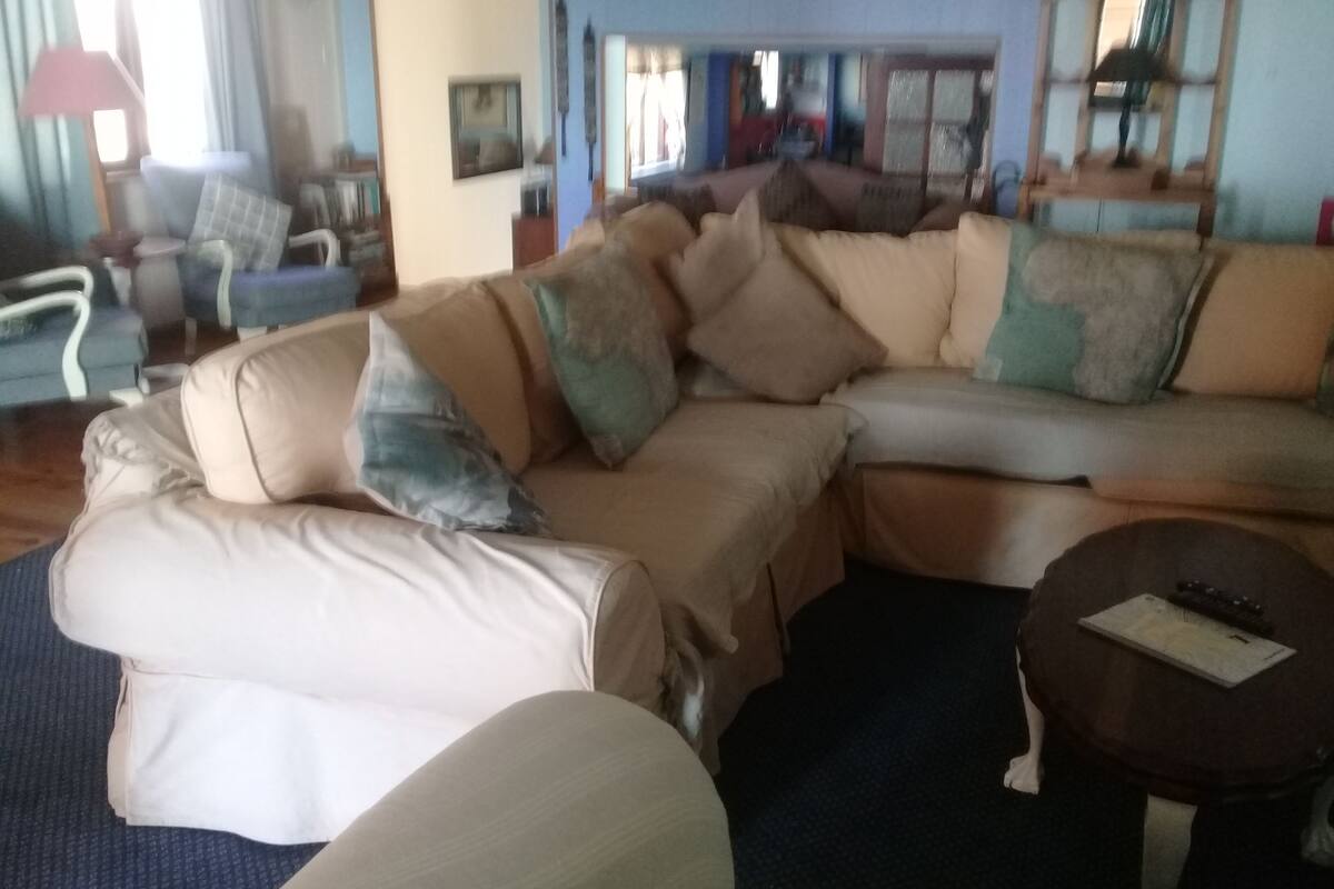 A living room with a beige sectional sofa, a small round table, and a blue carpet.