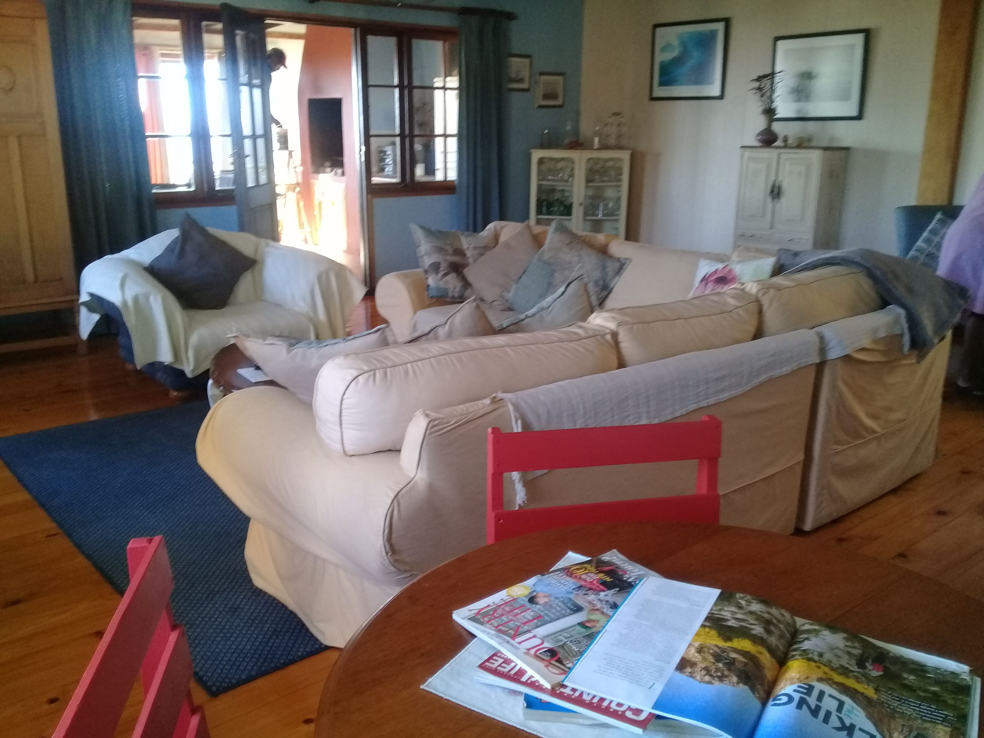Ett vardagsrum med en beige soffa, en röd fåtölj och ett bord med tidningar.