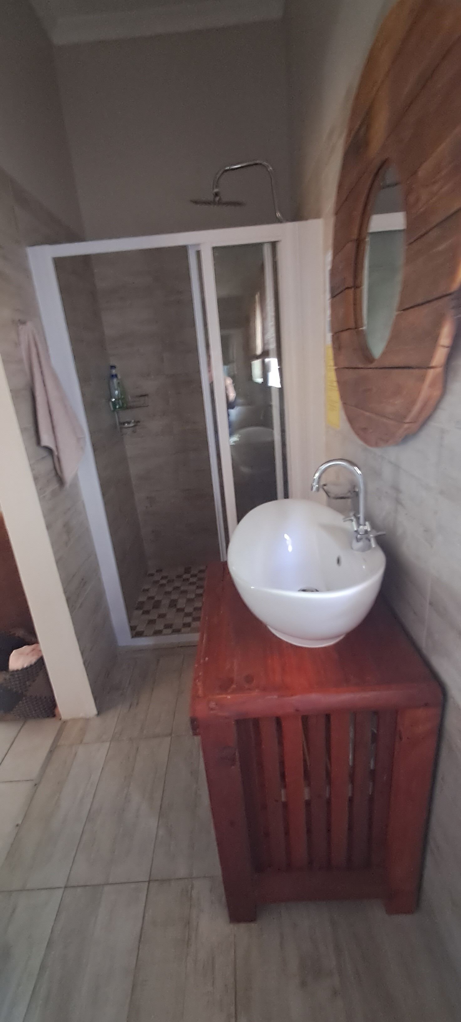 A bathroom with a white sink, wooden vanity, and a glass shower enclosure.