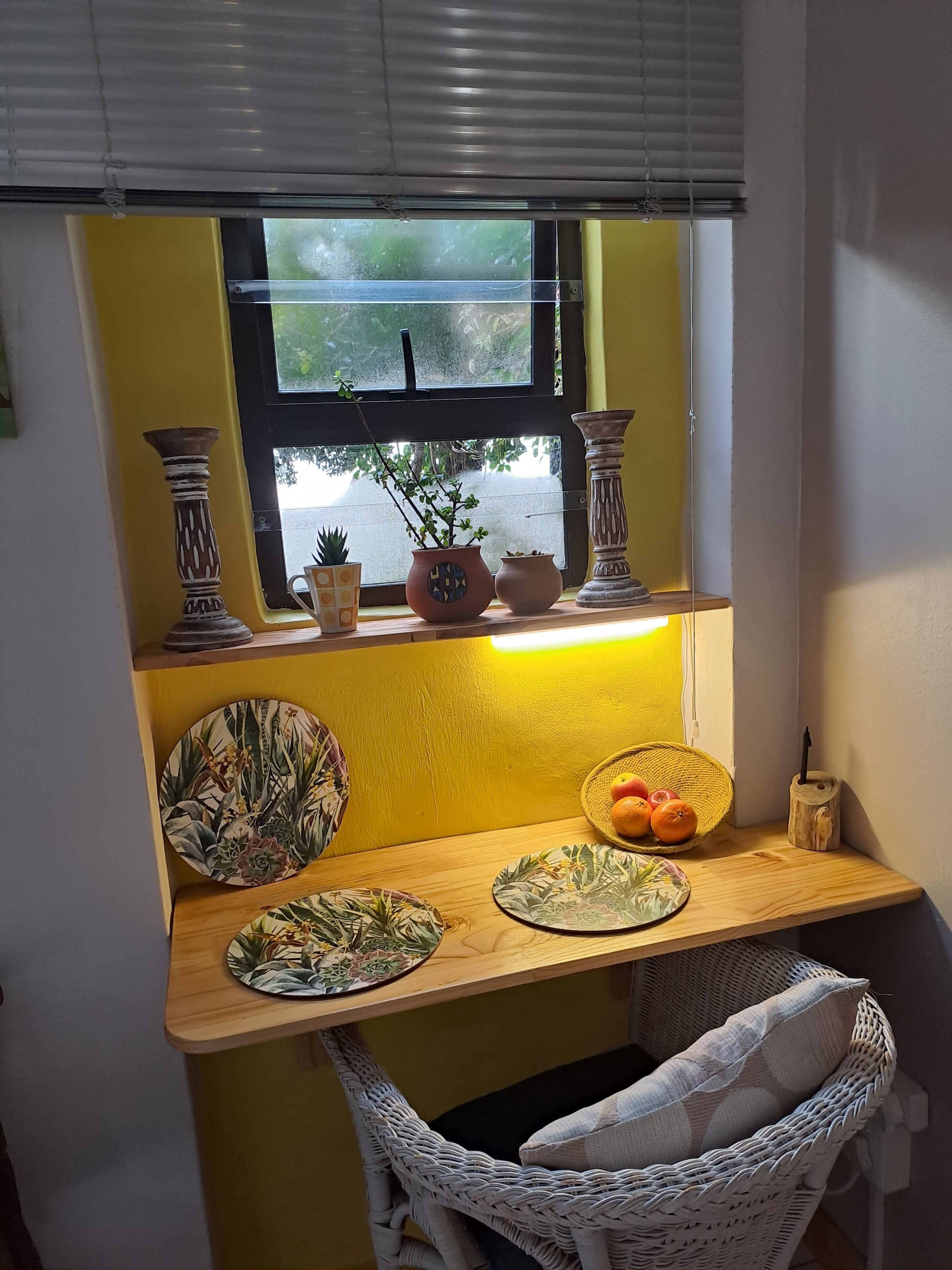 Un pequeño espacio de cocina con ventana, una mesa de madera y varios objetos decorativos.