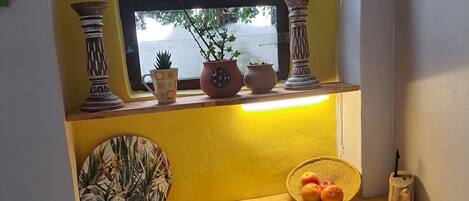 Un pequeño espacio de cocina con ventana, una mesa de madera y varios objetos decorativos.