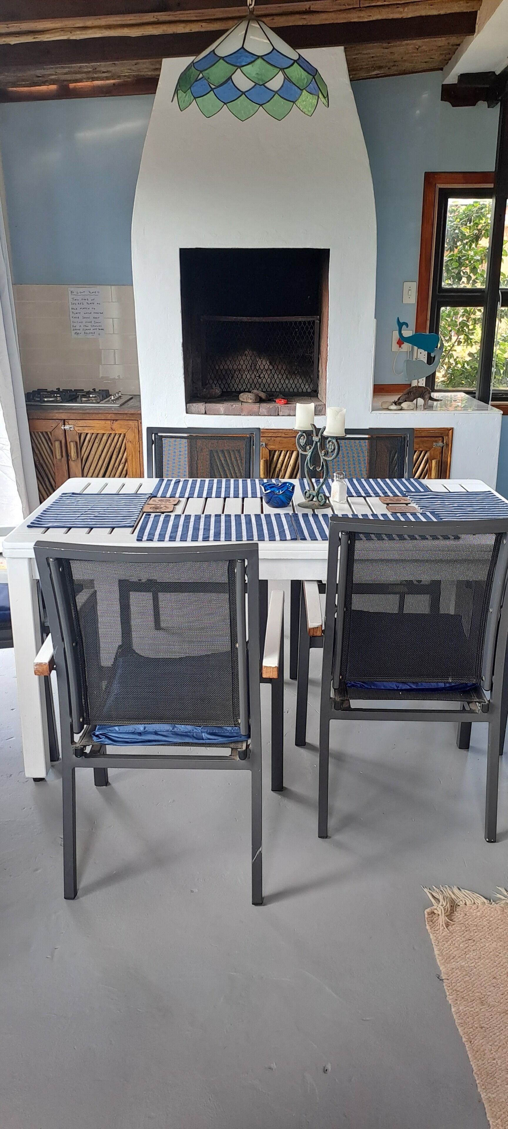Ein Essbereich mit einem weißen Tisch, blau gestreiften Untersetzern und schwarzen Netzsesseln.