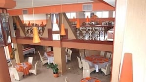 A multi-level restaurant with tables and chairs, a balcony, and hanging orange pendant lights.