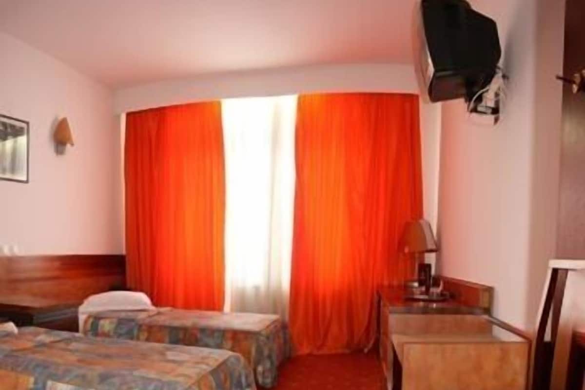 Ett hotellrum med två sängar, ett skrivbord, en stol och en tv.