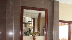 A lobby with a large mirror, black leather seating, and a tiled floor.