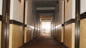 A long, narrow hallway with doors on both sides, leading to an open area at the end.