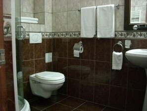 A bathroom with a toilet, a sink, and a shower area. - Black Lord Hotel (Tirgu Mures)
