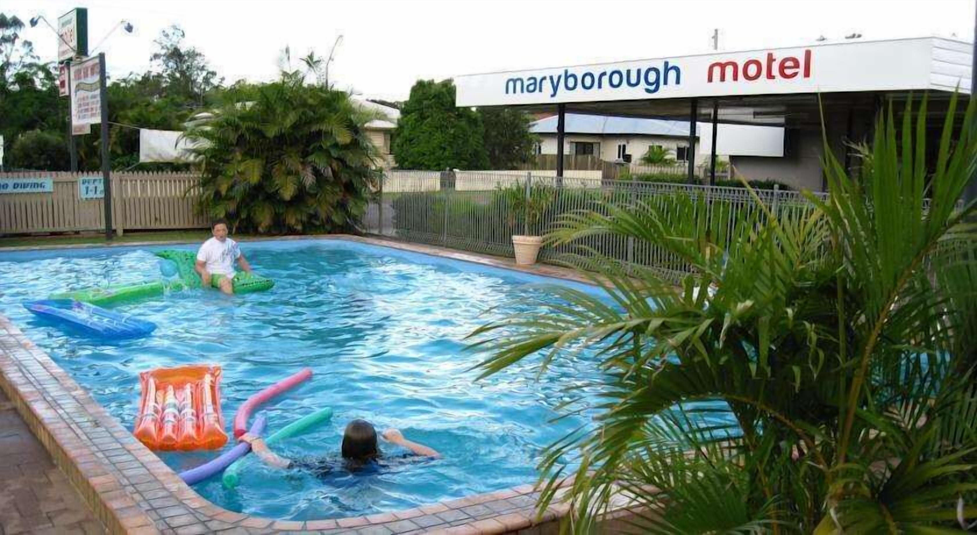 A swimming pool with inflatable toys and a sign for Maryborough Motel in the background.