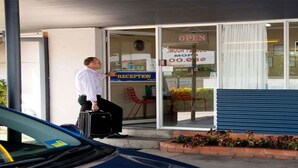 A hotel entrance with a reception desk, a sign indicating the price, and a man with luggage. - Maryborough Motel and Conference Centre (Maryborough)