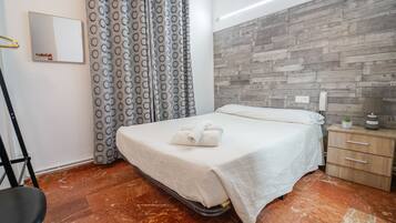Una habitación de hotel con una cama, un panel de madera, una mesita de noche y un espejo.