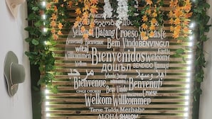 A reception area with a wall decorated with autumn leaves and a multilingual welcome sign. - Hostal Nevot (Granada)
