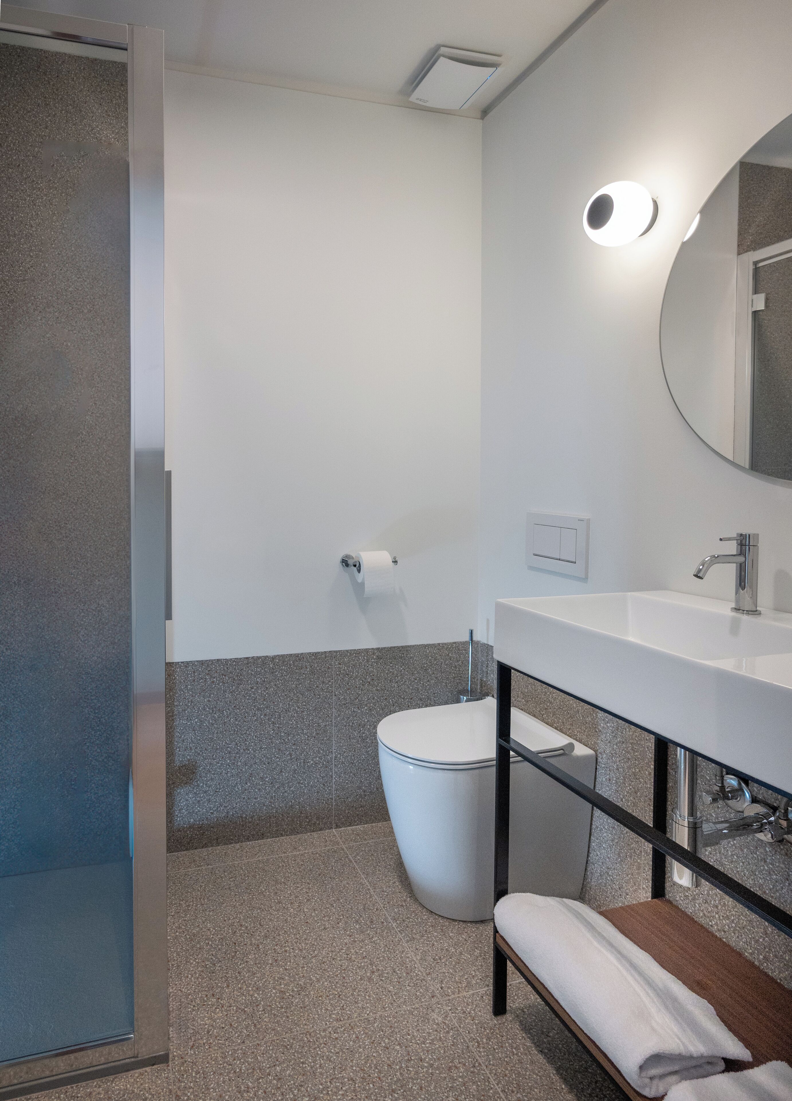 Un baño moderno con inodoro, lavamanos, espejo y toallero.