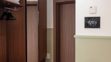 Ein Flur mit Holzboden, einem Spiegel, einem Kleiderschrank und einem Thermostat an der Wand.