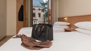 Hotelkamer met een bed, nachtkastje, koffer en uitzicht op een gebouw met een koepel.