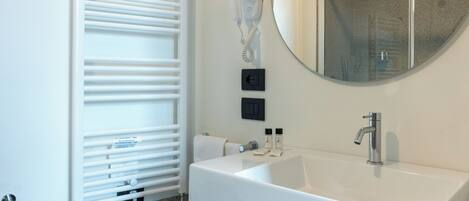 A modern bathroom with a white sink, a mirror, a towel rack, and a bidet.