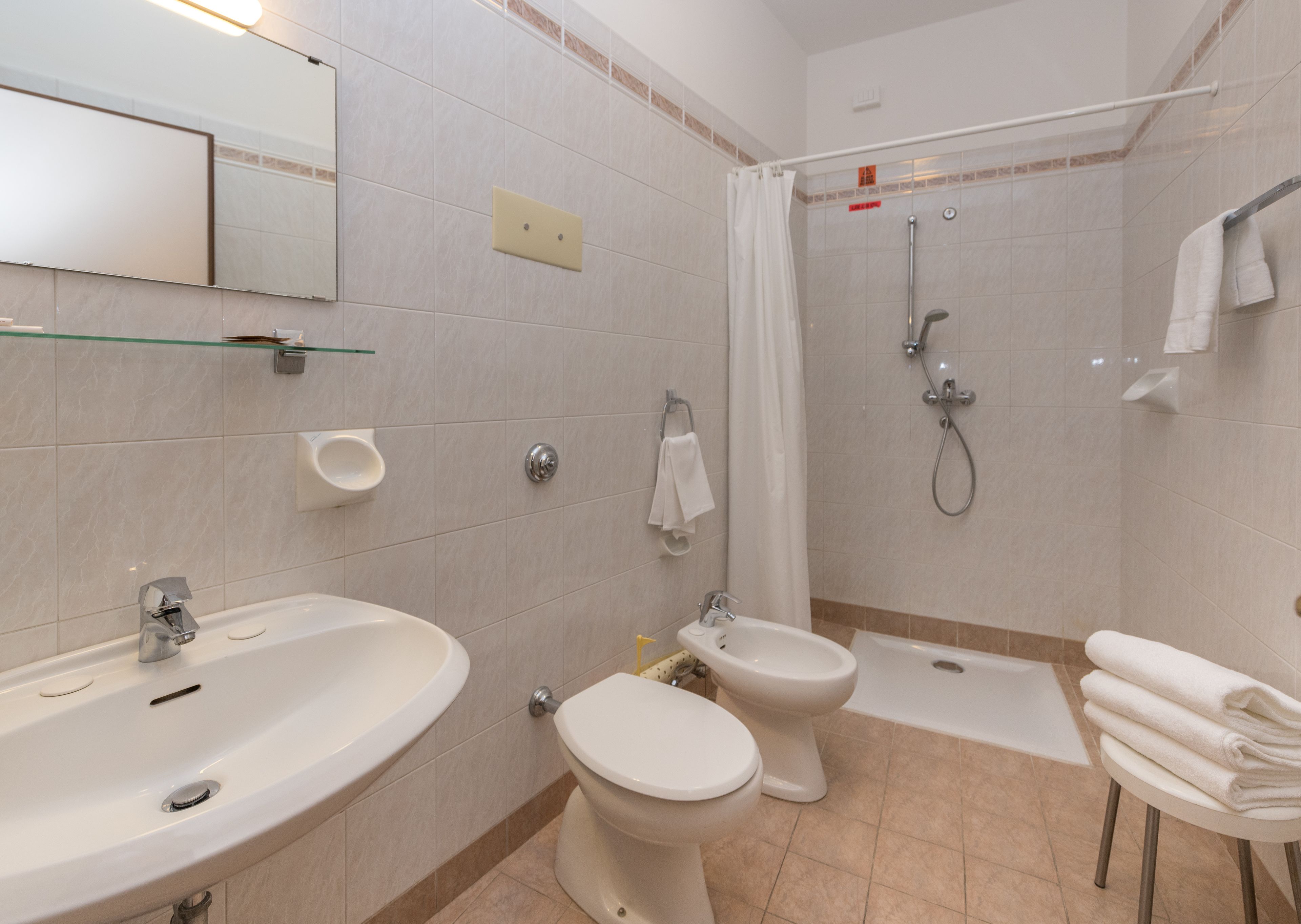 A modern bathroom with a sink, toilet, bidet, and shower.