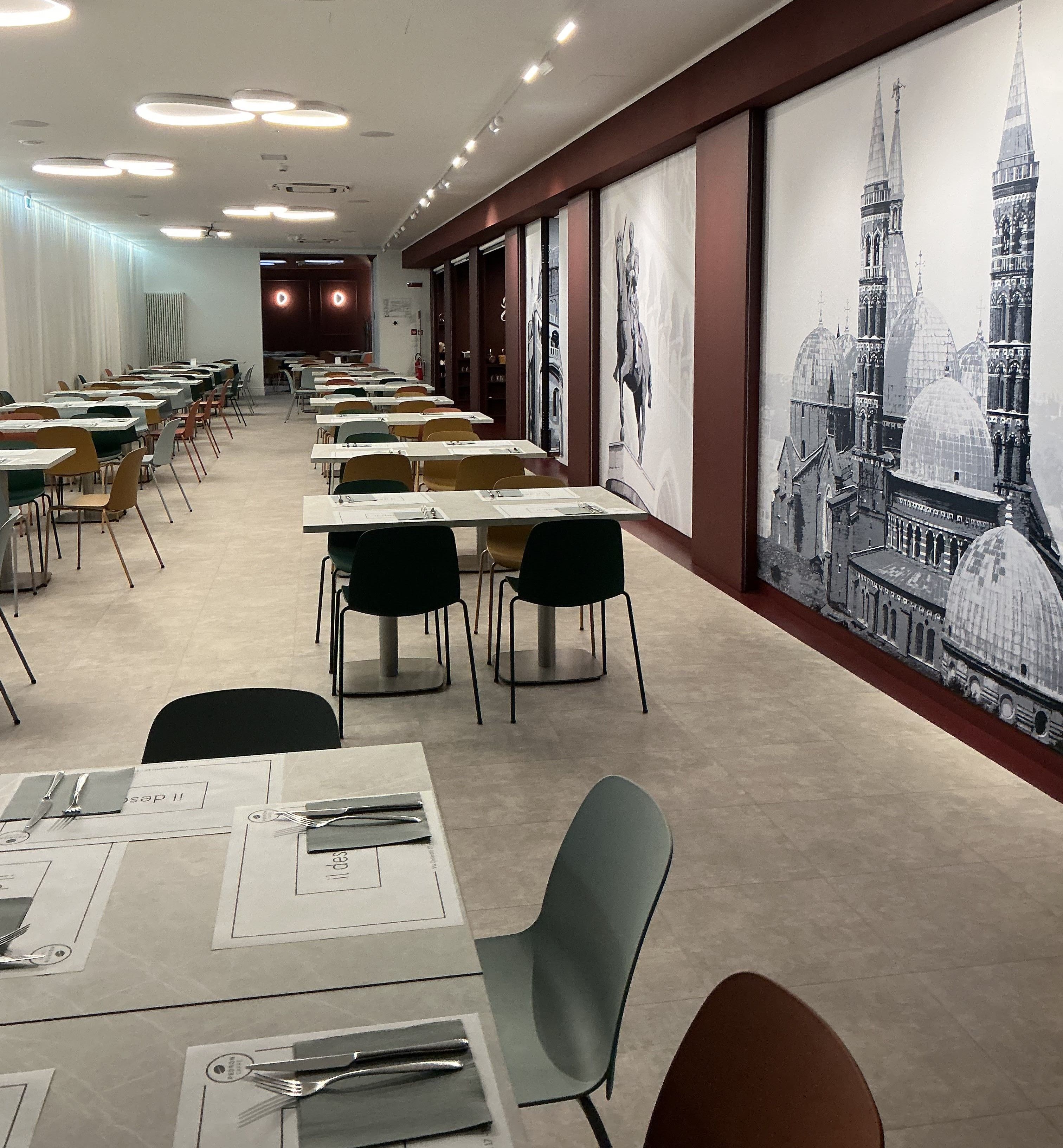 Un salón de conferencias con mesas dispuestas para una reunión, con un amplio mural de un paisaje urbano en la pared.
